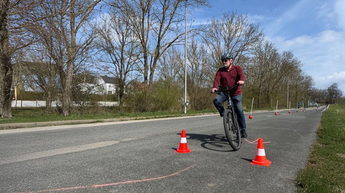 Ein Mann fährt mit dem Pedelec Slalom durch Pylonen. 