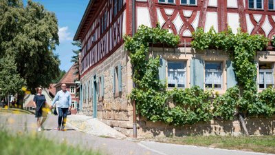 Paar spaziert an einem Fachwerkhaus vorbei.