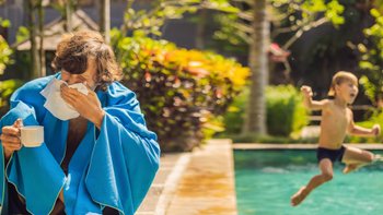kranker Mann am Pool, im Hintergrund Kind das in den Pool springt.