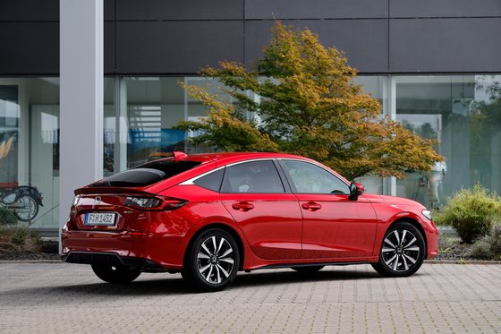 Ein roter Honda Civic 2025 parkt vor einem modernen Bürogebäude.