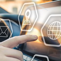 Eine Hand ist am Steuer, die andere tippt auf dem Auto Display herum.