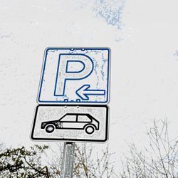 Ein Parkplatzschild mit einem Autosymbol darunter.