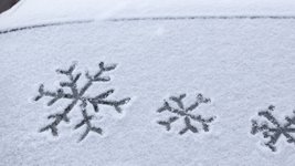 Schneebedeckte Autoscheibe mit Schneeflockensymbolen.