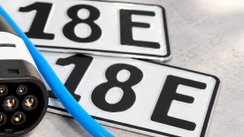 Zwei Kennzeichen eines E-Autos liegen auf dem Boden mit einem Elektrostecker. 