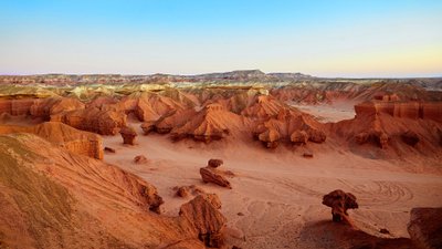 Landschaft mit Gesteinsformationen, die von Ocker über Gelb in verschiedene andere Farbschattierungen wechseln.