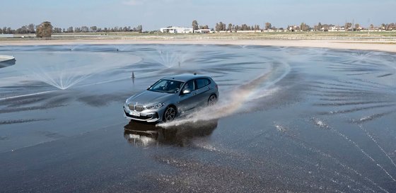 Auto, welches auf einer nassen Fahrbahn fährt.