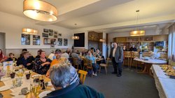 OC-Mitglieder sitzen im Clublokal zusammen bei einer Rede