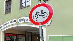Zwei Polizisten stehen an einem Durchgang und kontrollieren Radfahrer. 