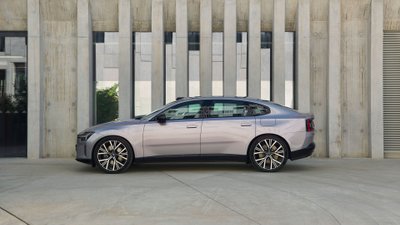 Seitenansicht des Volvo ES90 vor einem modernen Gebäude aus Beton.