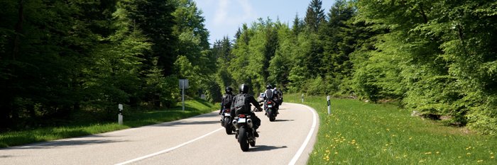 Motorradfahrer auf einer Waldstraße.
