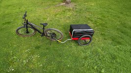 Der Fahrradanhänger Hinterher Hmax light mit der Falttasche auf einer Wiese mit Fahrrad 