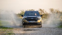 Subaru Forester fährt durch eine große Pfütze, das Wasser spritzt zur Seite.