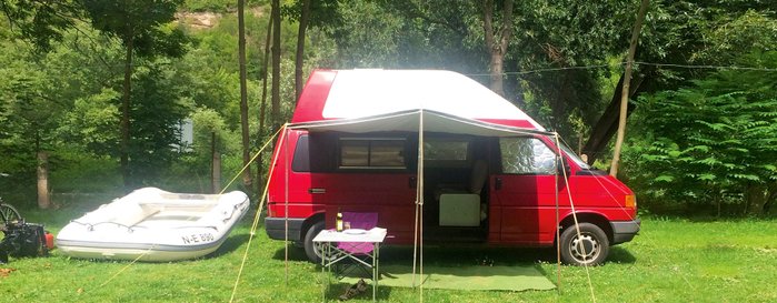 Ein fertig aufgebauter roter Camper mit Überdachung vorne.