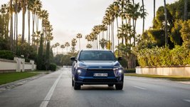 Der Toyota bZ4X auf einer Straße mit Palmen-Allee. 