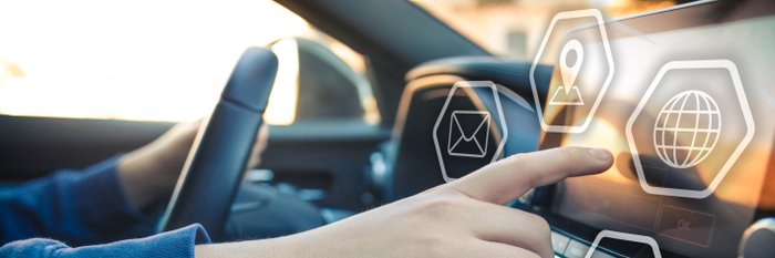 Eine Hand ist am Steuer, die andere tippt auf dem Auto Display herum.