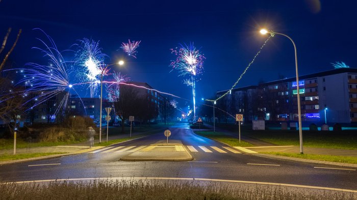 Silvesternacht auf einer Straßenkreuzung mit Böllern und Raketen.