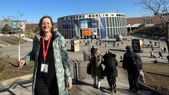 Frau steht vor Messehalle auf einer Treppe.