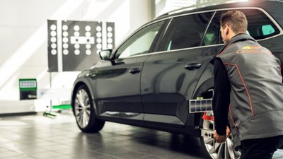 Mann kniet neben einem Auto. 