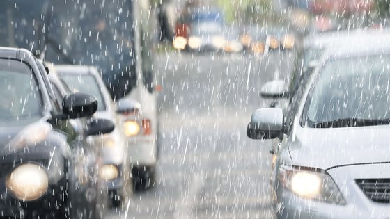 Straße mit Autoverkehr bei stärkerem Regen.