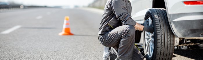 Mann, der auf der Straße seinen Reifen wechselt.