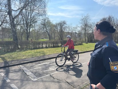 Eine Frau bekommt das Linksabbiegen von einer Polizistin erklärt. 
