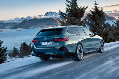 BMW i5 fährt über eine schneebedeckte Straße. 