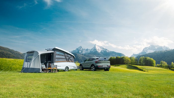 Easy Caravanning TakeOff steht aufgeklappt auf einem Campingplatz mit E-Auto als Zugfahrzeug.