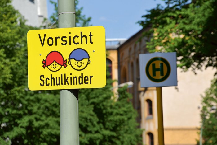 Ein Schild an einer Bushaltestelle mit dem Aufdruck "Vorsicht Schulkinder".
