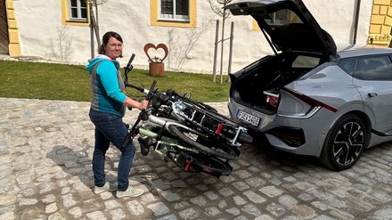 Frau hält Fahrräder auf Fahrradträger. 