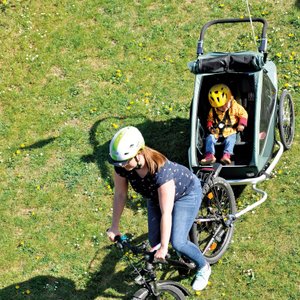 Der Fahrradanhänger Croozer Kid Vaaya auf einer Wiese stehend.