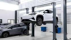  Ein E-Auto steht reparaturbereit auf einer Hebebühne in einer Werkstatt.