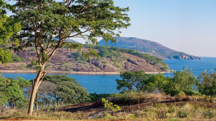 See mit hügeligem Ufer und grünen Bäumen.