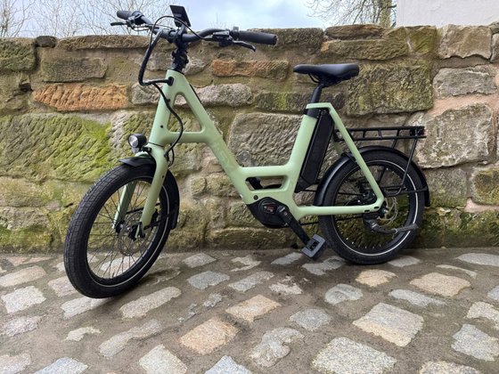 Grünes Fahrrad steht vor einer Mauer. 