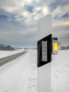 Sensor für Wildwarnung an einem Leitpfosten in Nahaufnahme.