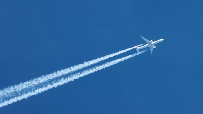 Flugzeug erzeugt Kondensstreifen am Himmel.