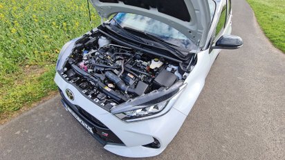 Ein Auto mit offener Motorhaube, der Motor ist zu sehen.