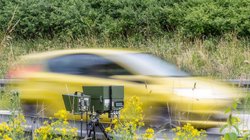 Ein gelbes Auto fährt in eine Geschwindigkeitskontrolle. 