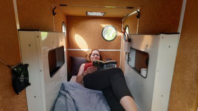 Eine Frau liegt im Fahrradanhänger Martha und liest ein Buch.