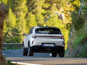 Heckansicht des Opel Grandland PHEV auf einer Landstraße im Sommer.