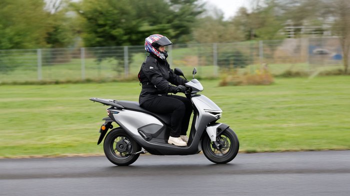 Eine Frau fährt den Elektroroller Honda CUV e