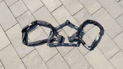 Ein Kettenschloss, ein Faltschloss und ein Fingerprint-Schloss liegen aufgereiht auf dem Boden.