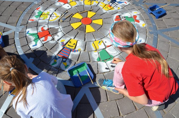 Kinder malen mit Farbe und Kreide auf die Straße.