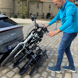 Mann kippt Fahrradträger ab. 