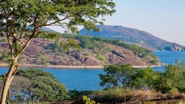 See mit hügeligem Ufer und grünen Bäumen.