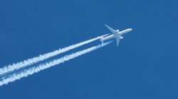 Flugzeug erzeugt Kondensstreifen am Himmel.