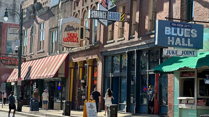 Belebte Straße mit Leuchtreklamen von Musikclubs und Restaurants.