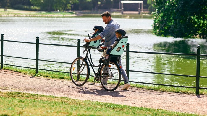 Ein Radfahrer ist mit einem Kindersitz vorne und hinten unterwegs.