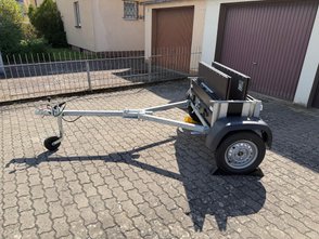 Teilweise zusammengefalteter Faltos-Anhänger steht in einer Einfahrt. 