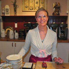 Lachende Frau hinter dem Tresen in einem Kaffee.