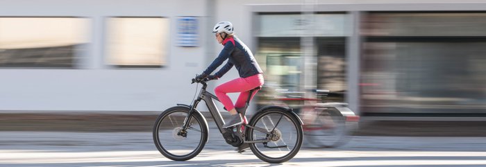 Ein E-Bike-Fahrer fährt auf einer Straße durch die Stadt. 